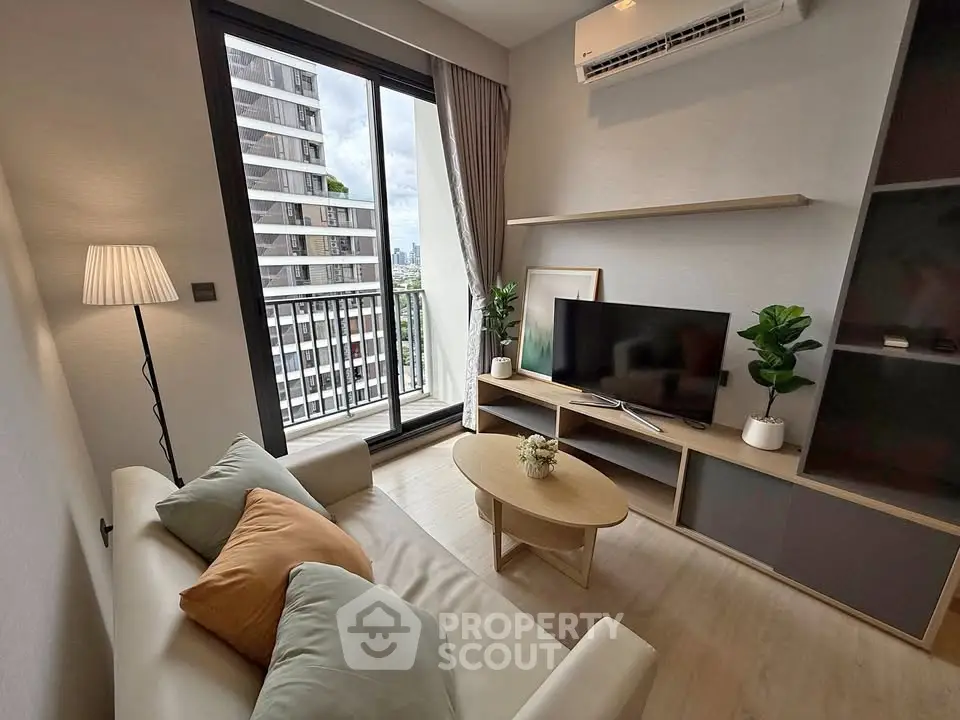 Modern living room with balcony view, stylish furniture, and natural light in urban apartment.