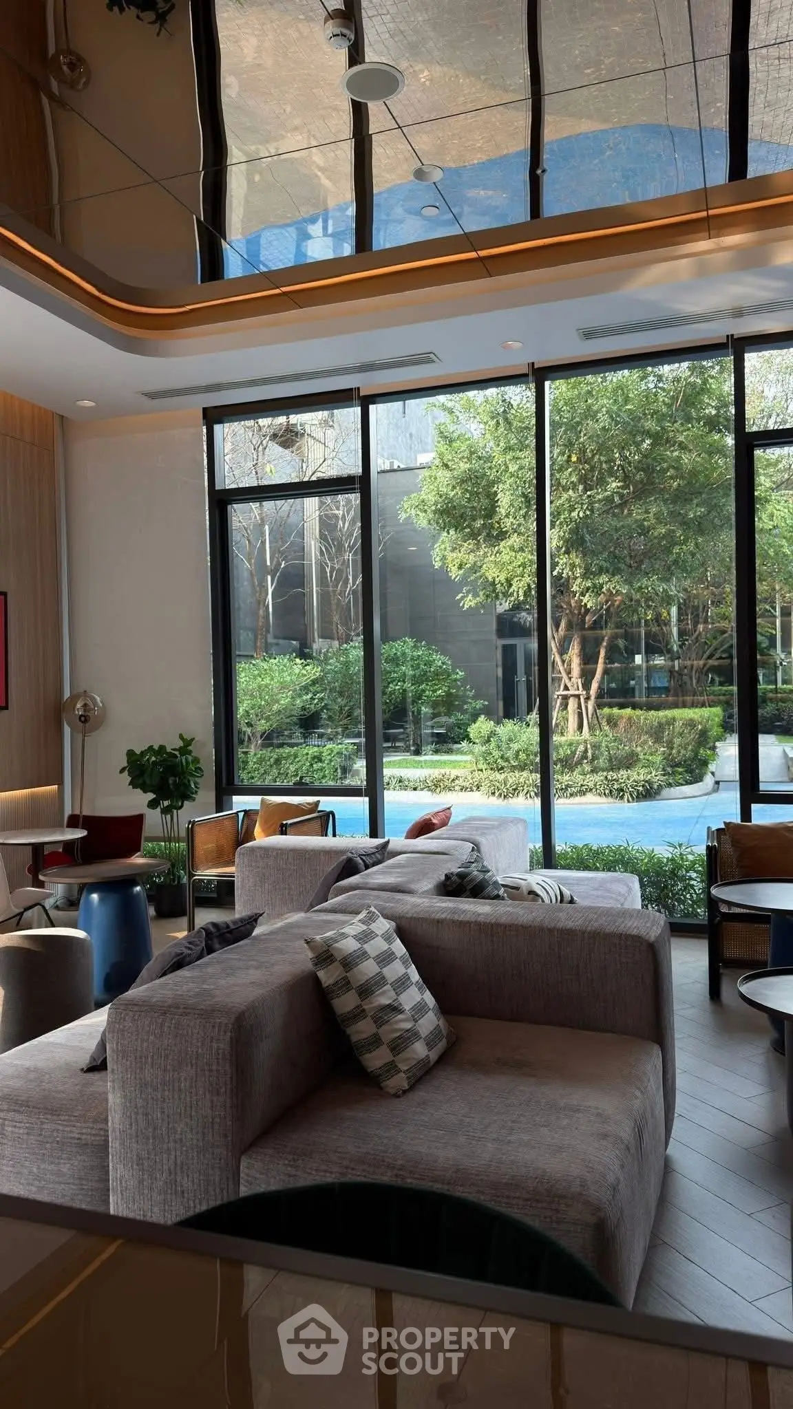 Luxurious living room with floor-to-ceiling windows and garden view, modern furniture and elegant decor.