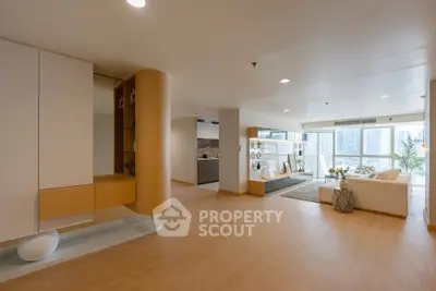 Spacious modern living room with open layout and city view, featuring elegant decor and natural light.