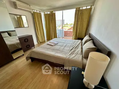 Spacious bedroom with modern furnishings and large windows offering natural light.