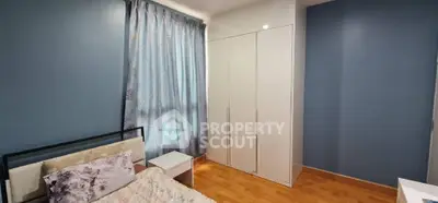 Cozy bedroom with blue walls, white wardrobe, and floral curtains