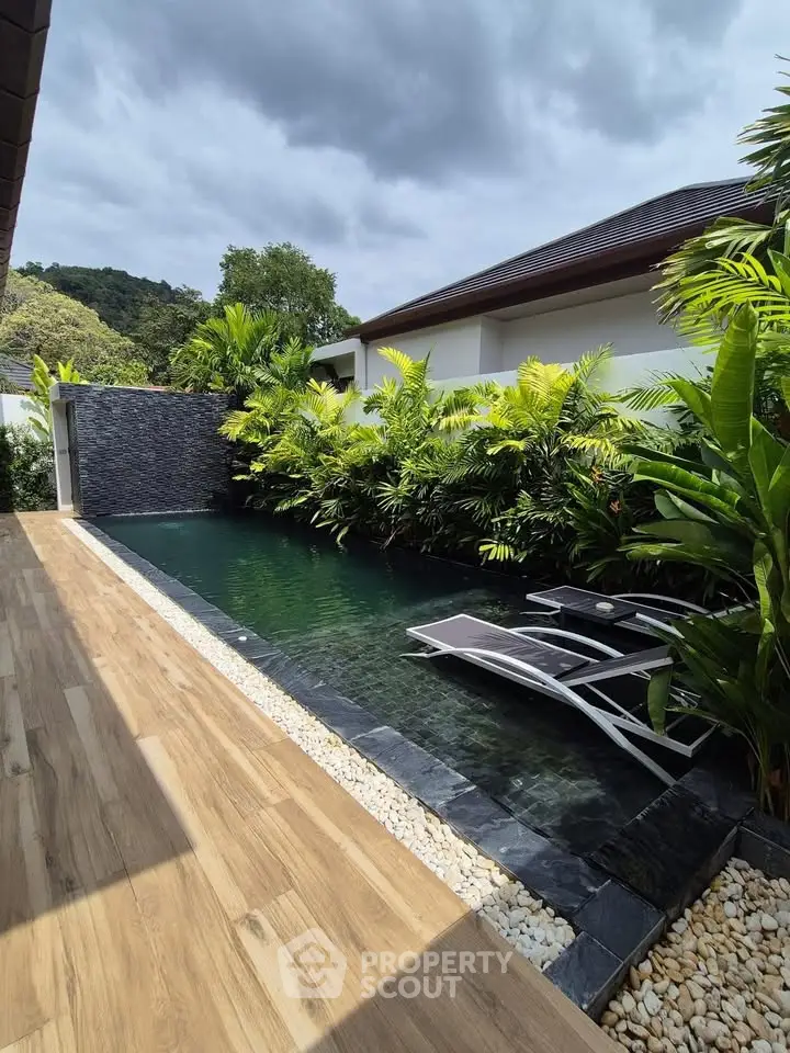 Luxurious private pool with lush greenery and modern sun loungers in a serene villa setting.