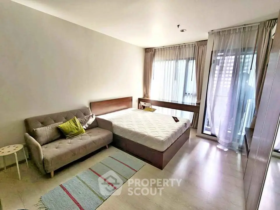Modern bedroom with cozy sofa and natural light, featuring stylish decor and spacious layout.
