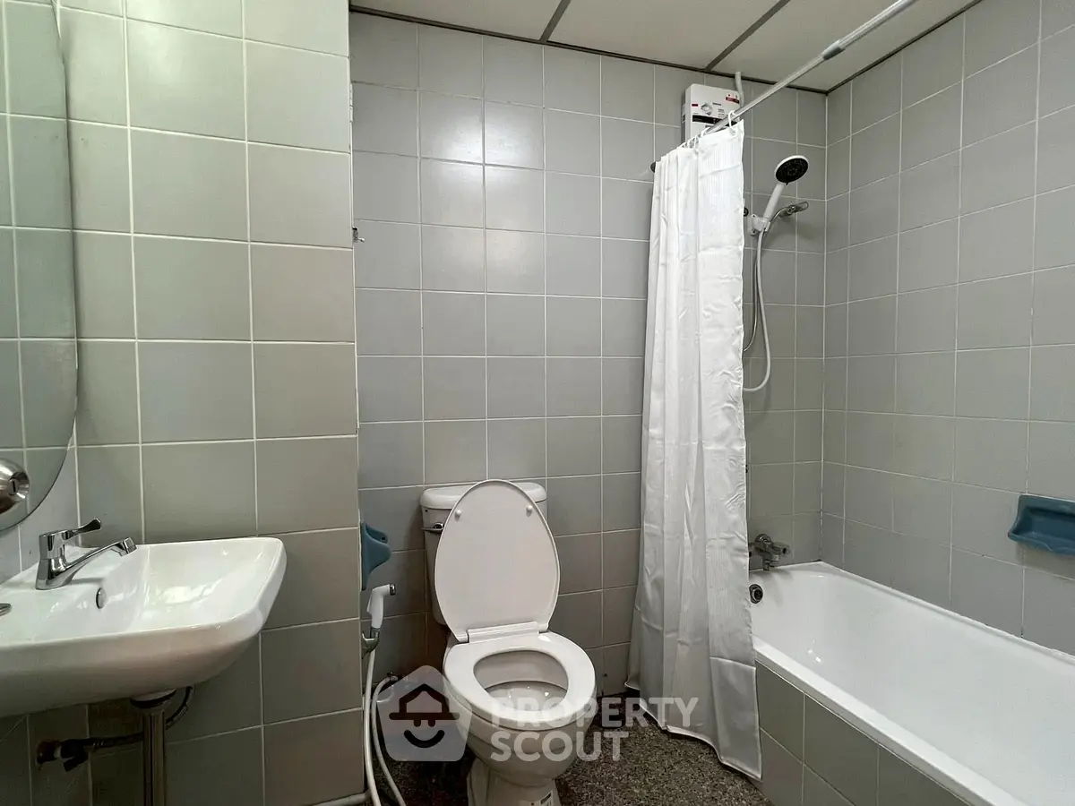 Modern bathroom with bathtub and shower in sleek tiled design.