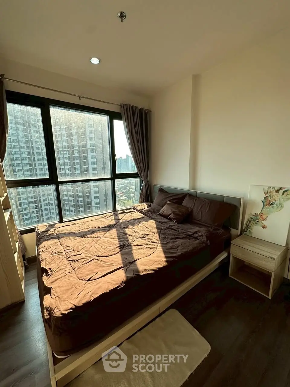 Cozy bedroom with large window offering stunning city view in modern apartment