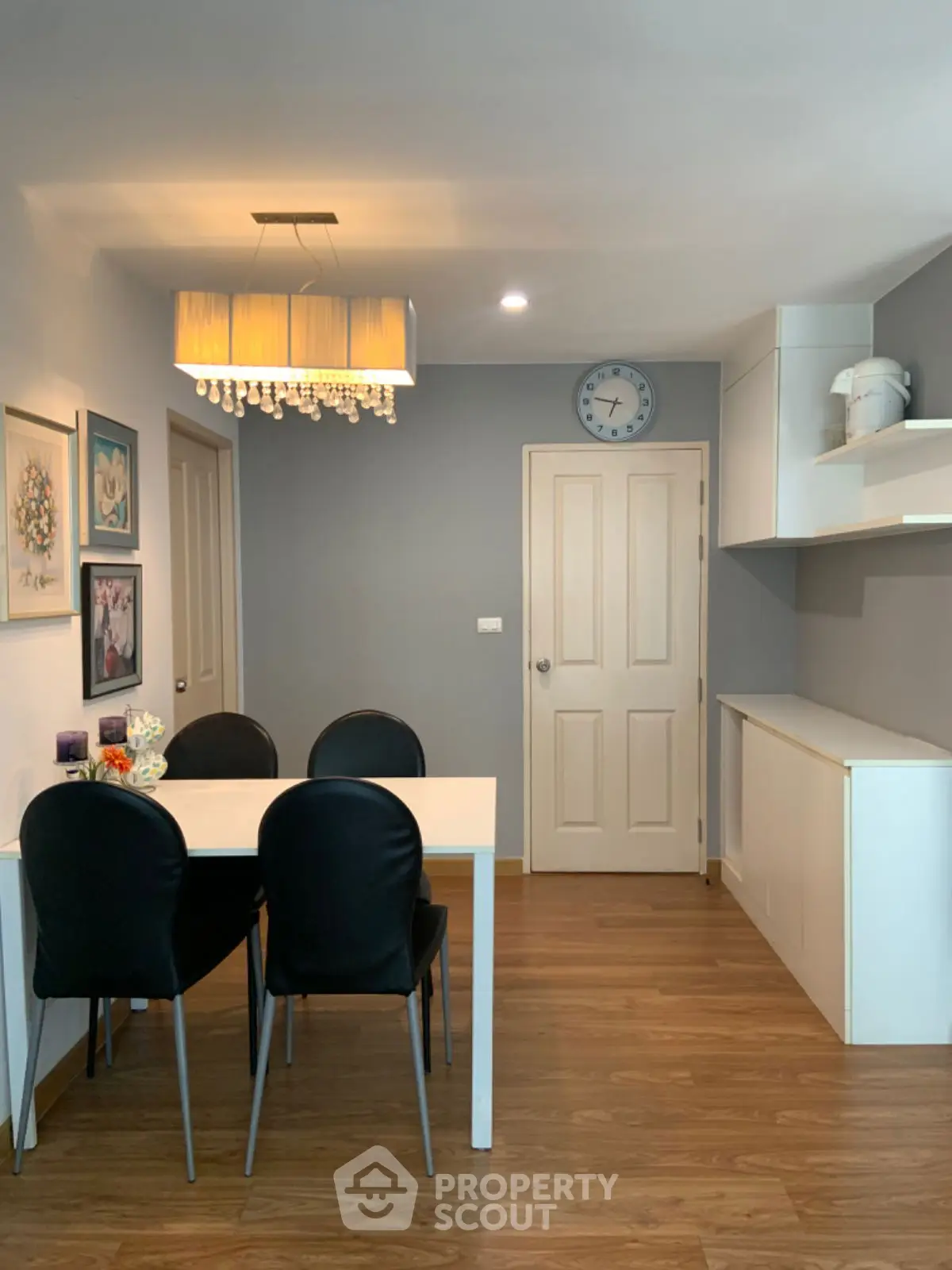 Stylish dining area with modern chandelier and wooden flooring in cozy apartment.