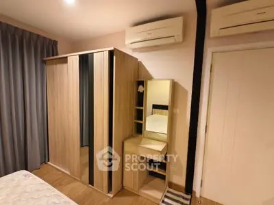 Modern bedroom with wooden wardrobe and vanity set, featuring dual air conditioning units.