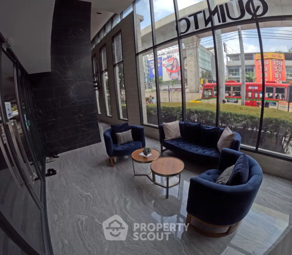 Modern building entrance with stylish seating area and large windows offering city views.