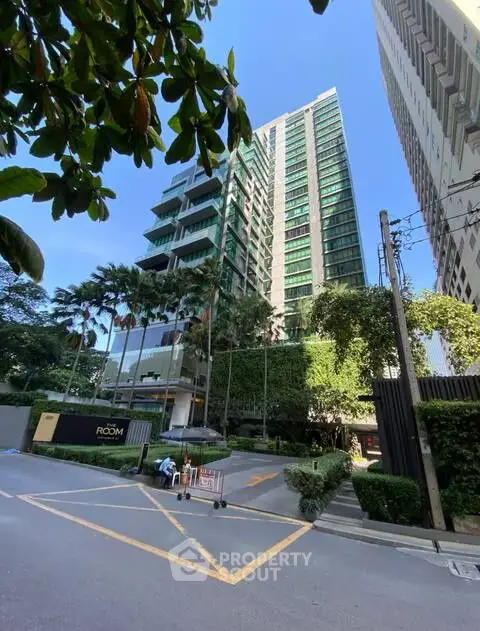 Modern high-rise building with lush greenery and clear blue sky