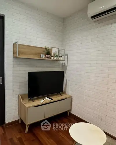 Modern living room with stylish TV setup and wooden flooring, featuring a sleek air conditioning unit.