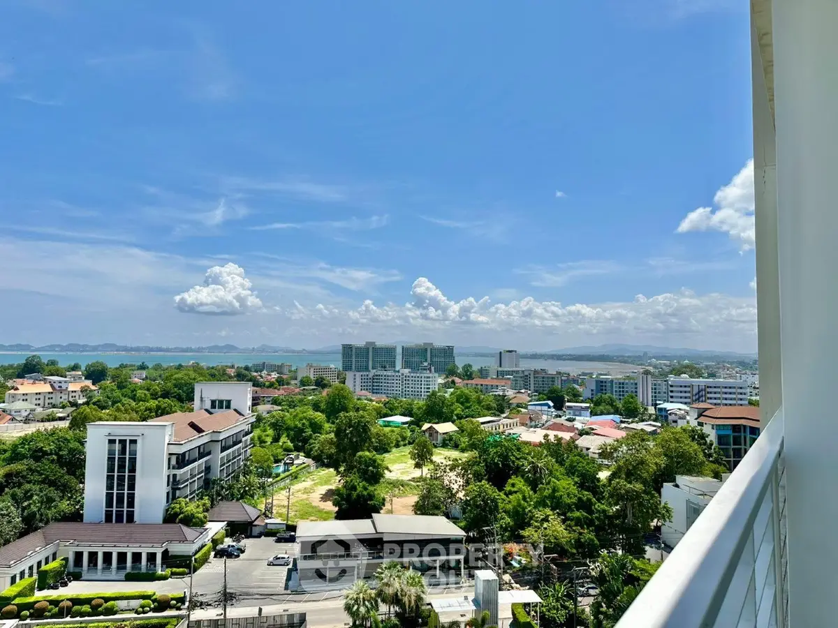 Stunning cityscape view from a high-rise balcony with lush greenery and clear blue skies.