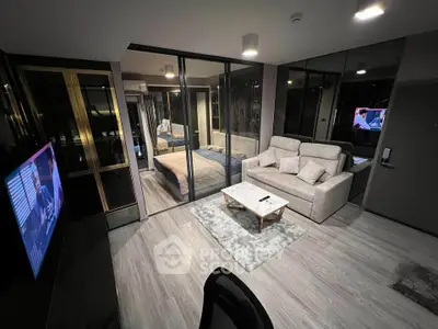 Modern living room with glass wall bedroom, stylish sofa, and sleek TV setup in a contemporary apartment.