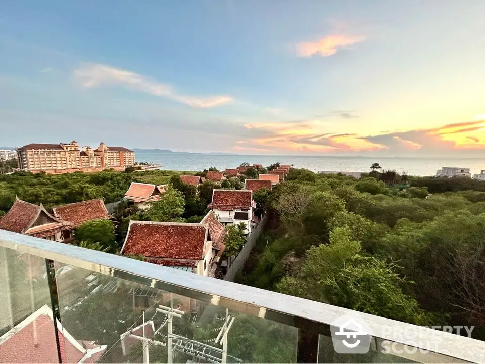 Stunning ocean view from a high-rise balcony overlooking lush greenery and traditional architecture.