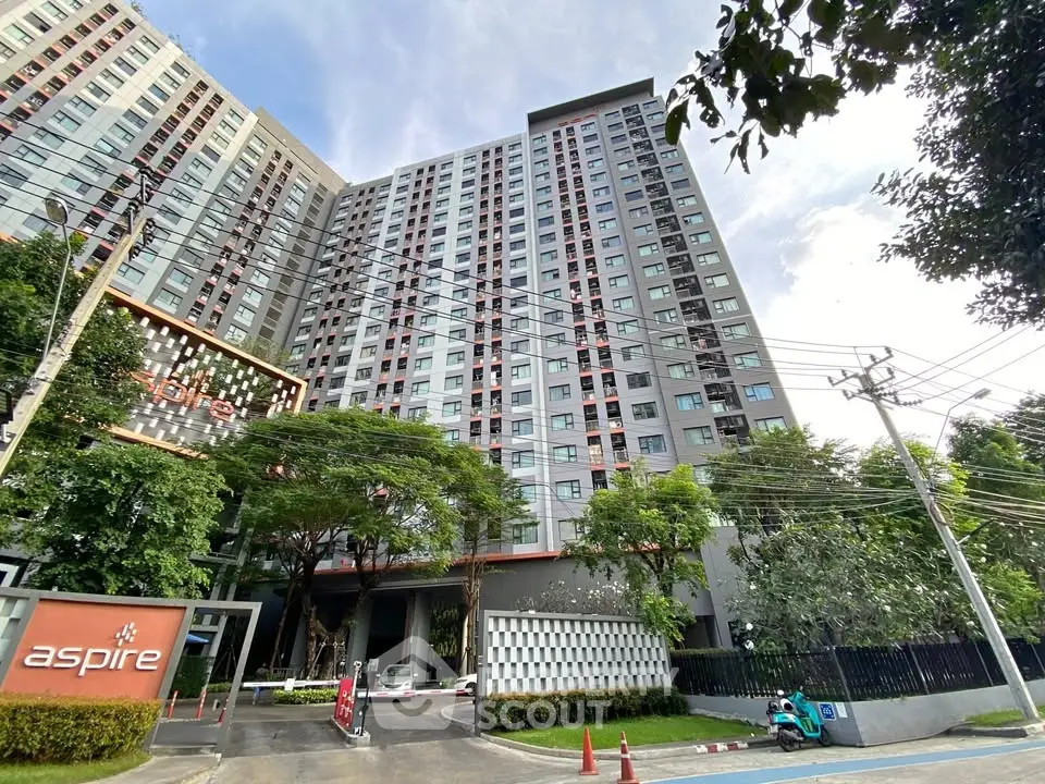 Modern high-rise condominium building with lush greenery and secure entrance.