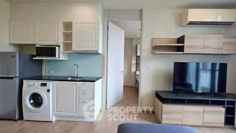 Modern apartment interior with kitchen and living area featuring sleek appliances and stylish cabinetry.