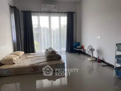 Spacious bedroom with large windows and minimalist decor, offering serene views and ample natural light.