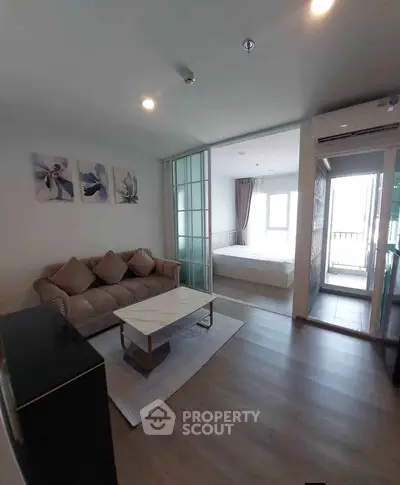 Modern living room with cozy sofa and elegant decor leading to a bright bedroom.