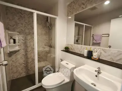 Modern bathroom with glass shower and sleek fixtures in contemporary apartment.