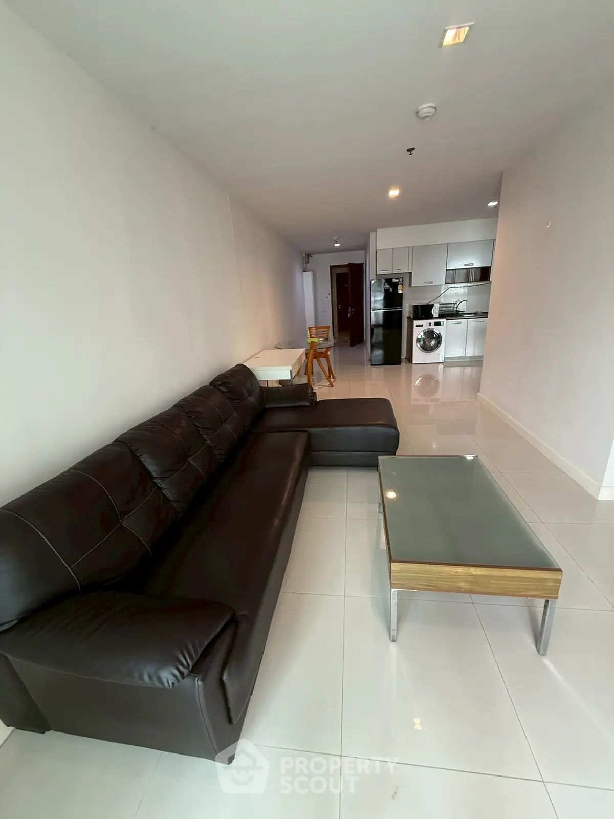 Spacious modern living room with sleek leather sofa and open kitchen layout