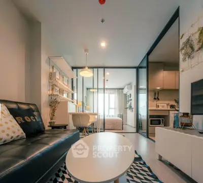 Modern living room with stylish decor and open layout leading to bedroom and kitchen.