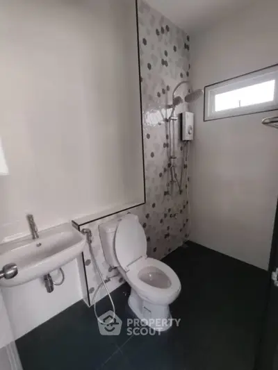 Modern bathroom with sleek fixtures and stylish tile design, featuring a compact layout and contemporary shower.