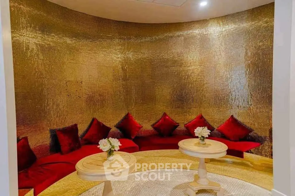 Luxurious gold-themed lounge with red velvet seating and elegant decor
