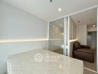 Modern bedroom with sliding glass doors and cozy seating area in a stylish apartment.