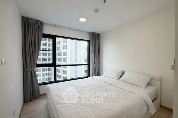 Modern bedroom with large window and city view in high-rise apartment