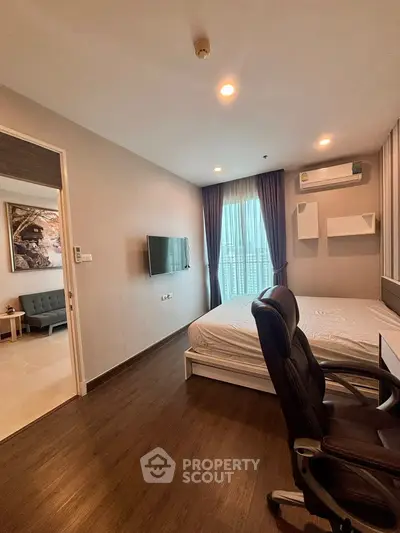 Modern bedroom with sleek design, featuring a wall-mounted TV and a comfortable workspace.