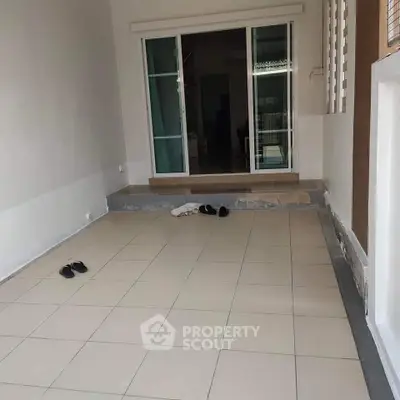 Spacious tiled patio area with sliding glass doors leading to interior space.