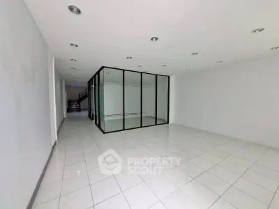Spacious modern interior with glass partition and tiled flooring, ideal for office or retail space.