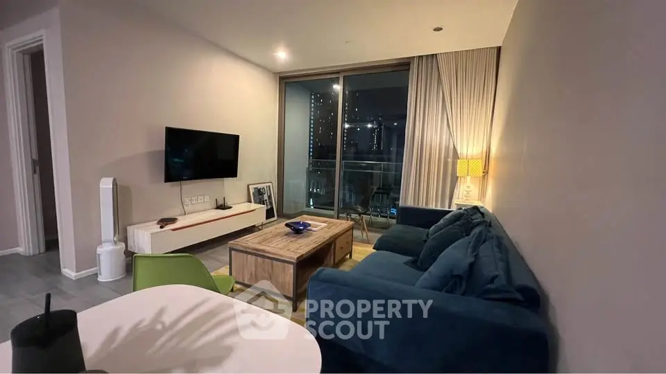 Modern living room with cozy blue sofa and balcony view in stylish apartment.