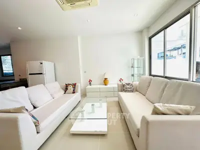 Spacious modern living room with white sofas and glass coffee table, perfect for relaxation and entertaining.