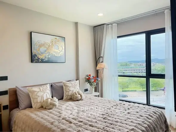 Modern bedroom with large window and stylish decor in a high-rise apartment.