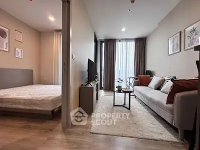 Modern apartment interior with cozy living room and adjacent bedroom, featuring stylish decor and natural light.