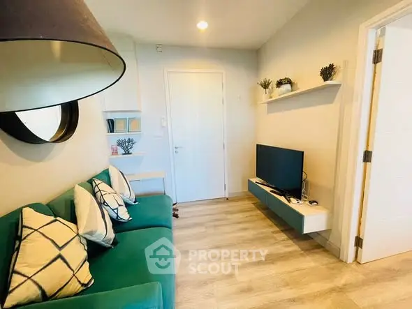Modern living room with green sofa and wall-mounted TV in cozy apartment.