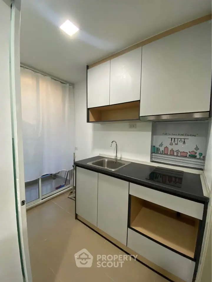 Modern compact kitchen with sleek cabinets and black countertop in a cozy apartment.
