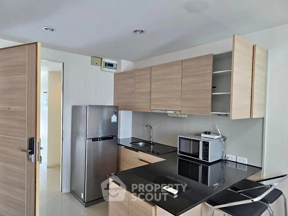 Modern kitchen with sleek cabinets, black countertops, and stainless steel appliances in a stylish apartment.