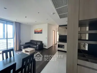 Modern living room with sleek furniture and large windows offering city views.