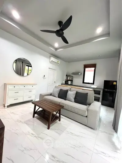 Modern living room with sleek furniture and stylish decor, featuring a cozy sofa and elegant ceiling fan.