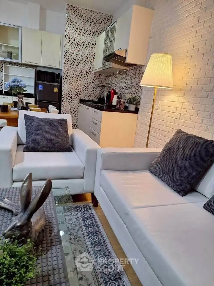 Modern living room with stylish kitchen, featuring sleek white sofas and contemporary decor.
