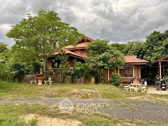 Charming rustic house with lush greenery and traditional architecture under a cloudy sky.