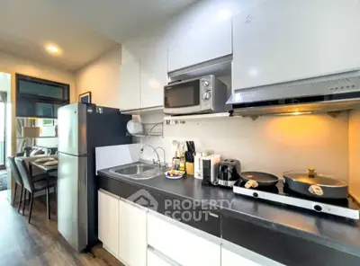 Modern kitchen with sleek appliances and open layout, featuring a microwave, fridge, and induction cooktop.