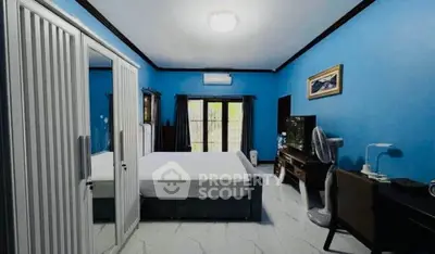 Spacious bedroom with blue walls, large mirrored wardrobe, and modern furnishings.