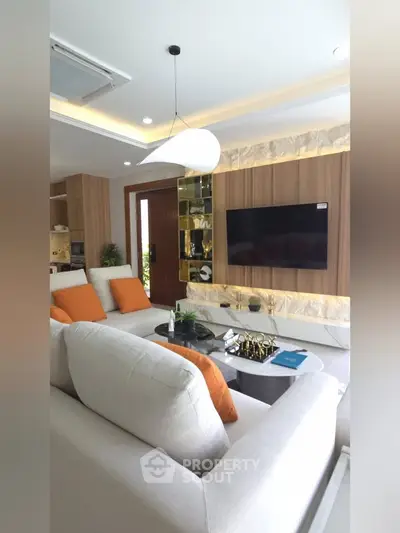 Modern living room with stylish decor and wall-mounted TV, featuring cozy seating and elegant lighting.