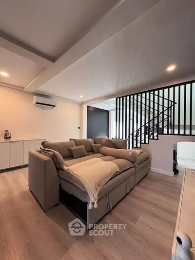 Spacious modern living room with cozy sectional sofa and stylish staircase