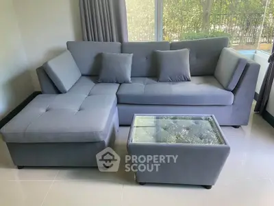 Modern living room with stylish gray sectional sofa and glass-top coffee table.