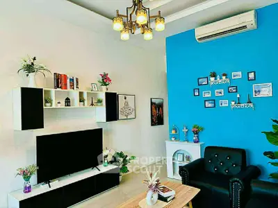 Stylish living room with modern decor, featuring a blue accent wall, elegant lighting, and cozy seating.