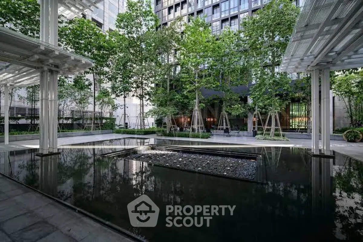 Luxurious modern building courtyard with serene water feature and lush greenery.