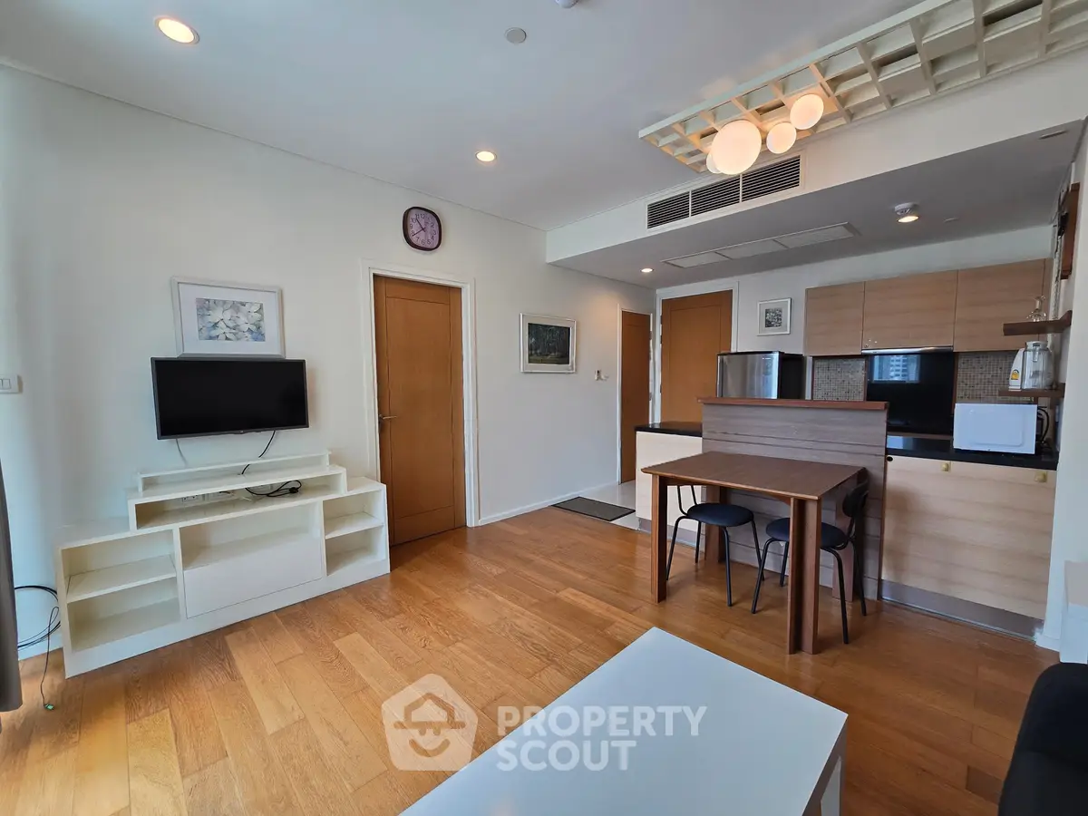 Modern living room with open kitchen, wooden flooring, and stylish decor in a cozy apartment.